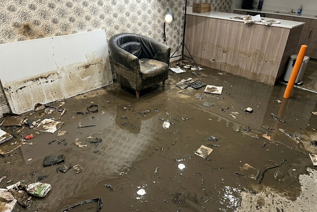 Before water damage restoration — flooded room with mud and debris